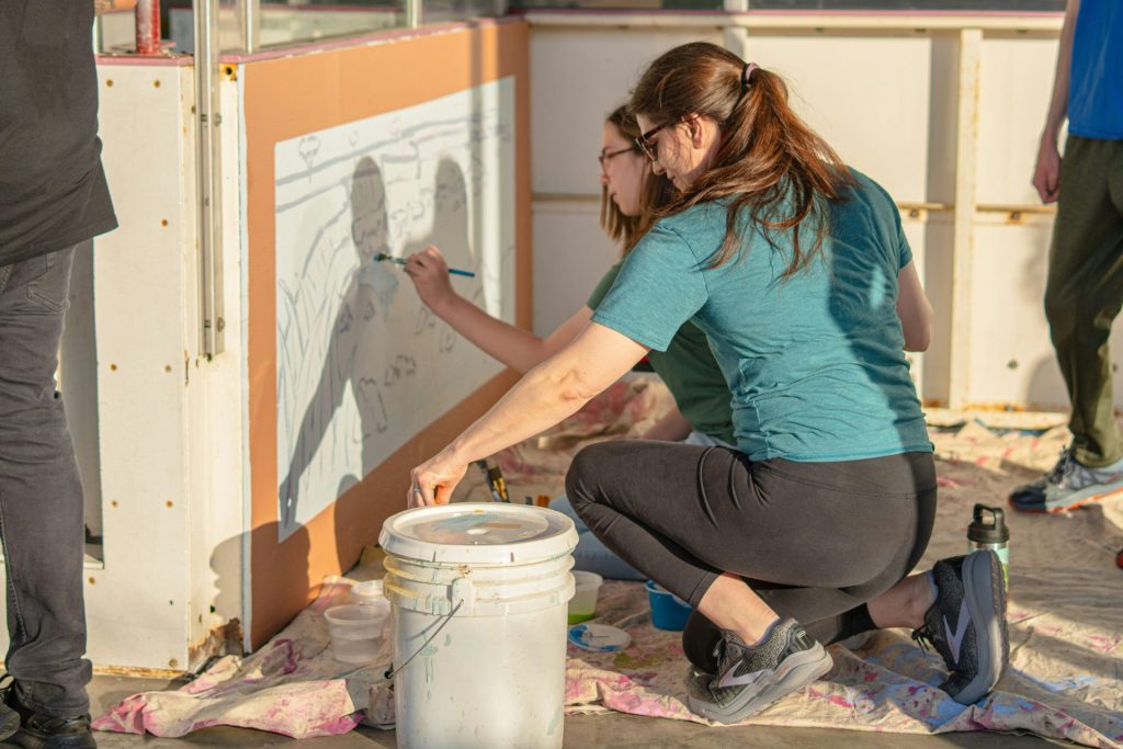 Two people are painting on a wall.